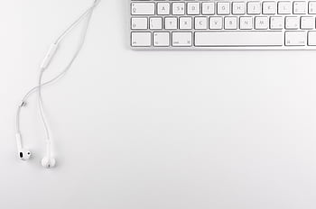 Top view of a minimal white desk setup featuring a keyboard and ears on a clean background. HD wallpaper