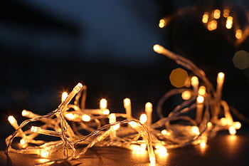 Close-up of warm LED string lights glowing against a dark background. HD wallpaper