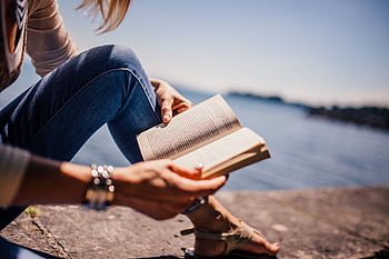 Serene of a young woman reading by the lake under a clear blue sky. HD wallpaper