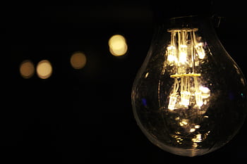 A glowing light bulb against a dark background, showcasing warm illumination. HD wallpaper