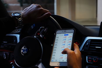 Person using mobile for currency trading while driving BMW car. HD wallpaper