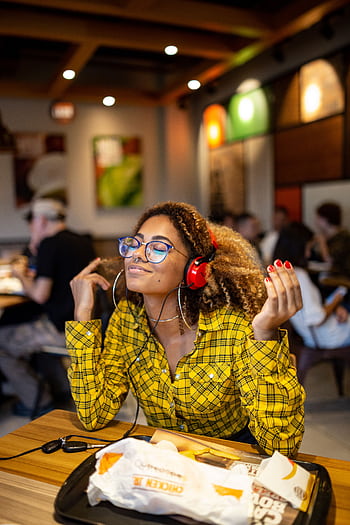 A stylish young woman with heads enjoying music at an indoor cafe. HD phone wallpaper