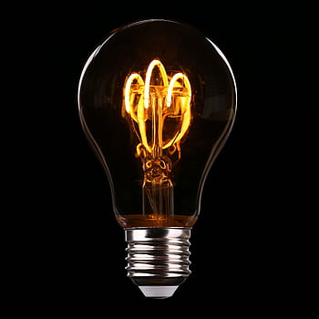 Close-up of an illuminated Edison-style light bulb on a dark background. HD phone wallpaper