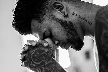 A man in deep thought and prayer, showcasing tattoos and an earring in a powerful black and white . HD wallpaper