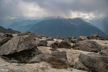 Breathtaking view of snow-capped mountain peaks under a cloudy sky. HD wallpaper