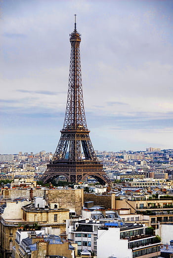 A captivating view of the Eiffel Tower rising above the Paris cityscape under a cloudy sky. HD phone wallpaper