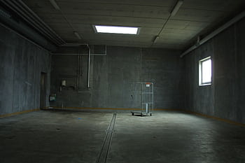 Dark empty industrial room with an abandoned cart, highlighting isolation and emptiness. HD wallpaper