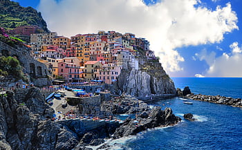 Vibrant houses perched on cliffs overlooking the sea in Manarola, Italy. HD wallpaper