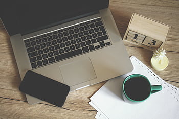 Modern office desk setup with laptop, smart, coffee, and calendar for productive work environment. HD wallpaper