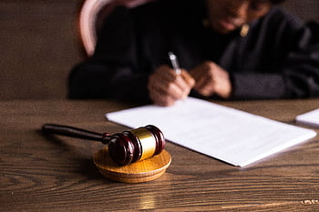 Judge signing documents at desk with focus on gavel, representing law and justice. HD wallpaper