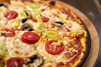 Close-up of a freshly baked Italian pizza topped with vibrant vegetables and cheese. HD wallpaper