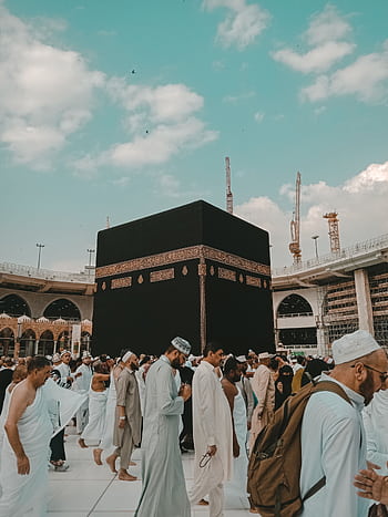 Pilgrims in traditional attire perform Tawaf around the Kaaba in Mecca, Saudi Arabia under a clear blue sky. HD phone wallpaper