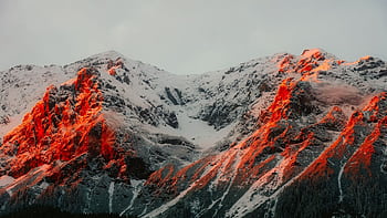 Sunlight casts a warm glow on a snowy mountain, creating a dramatic winter scene. HD wallpaper