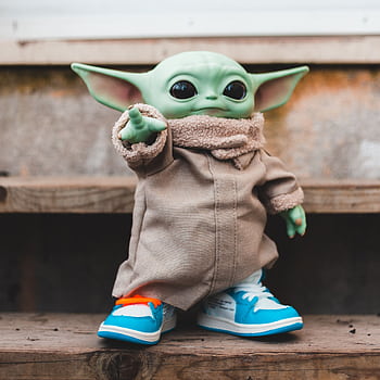 Adorable alien toy with stylish sneakers on rustic wooden steps, blending charm with fashion. HD phone wallpaper