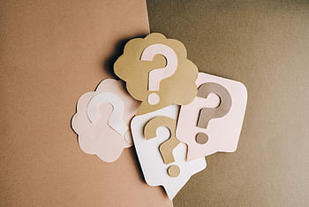 Question mark cutouts in layered paper craft style on a brown backdrop, conceptual art. HD wallpaper