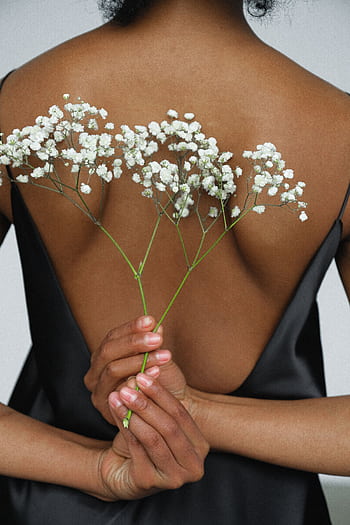 Aesthetic back view of a woman holding white flowers against an elegant black dress. HD phone wallpaper