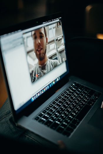 Close-up of a person engaged in a video call on a laptop indoors, showcasing modern technology. HD phone wallpaper