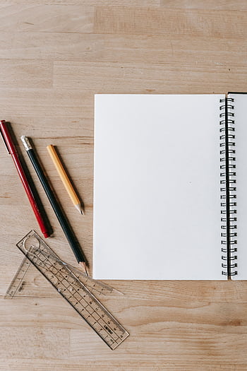 Overhead view of stationery items with blank notebook on a wooden desk, ideal for educational themes. HD phone wallpaper
