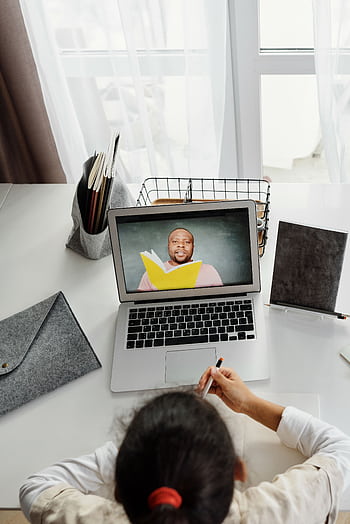 Child participating in an online class with a teacher, using a laptop at home, ideal for educational technology themes. HD phone wallpaper