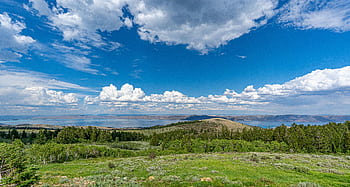 Stunning landscape of a lake surrounded by mountains with a vibrant blue sky and fluffy clouds. HD wallpaper