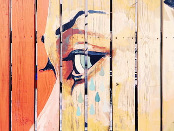 Vivid artistic mural depicting a crying eye painted on a natural wooden fence. HD wallpaper