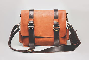 Elegant brown leather briefcase with dark straps and metal buckles, ideal for fashion and business. HD wallpaper