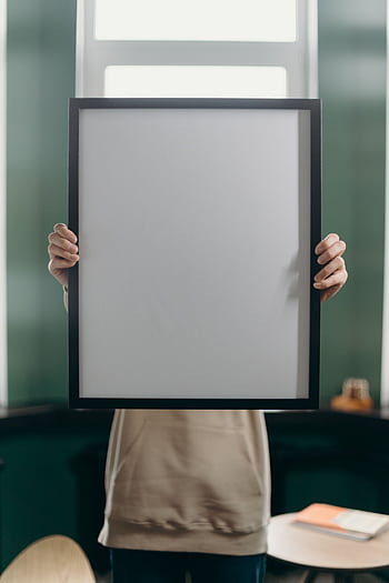 Anonymous person holds a blank vertical frame indoors against a window. HD phone wallpaper