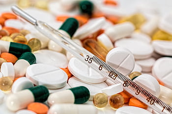 Close-up showing various pills and a thermometer, emphasizing health and medicine. HD wallpaper
