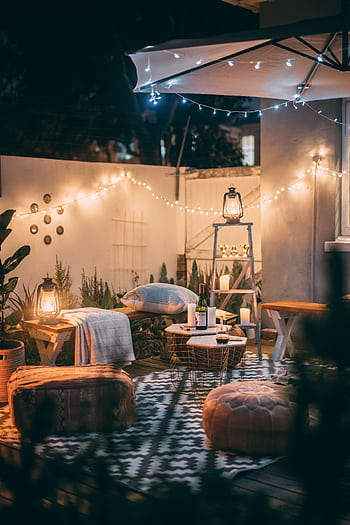 Warmly lit outdoor patio with cozy seating, lanterns, and decorative lights. HD phone wallpaper