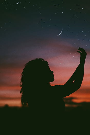 A silhouette of a woman extends her hand towards a starry sky with a crescent moon at twilight, conveying a sense of wonder and peace. HD phone wallpaper
