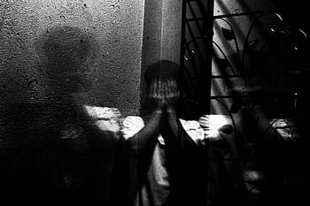 Grayscale of a man covering his face, evoking themes of fear and introspection. HD wallpaper