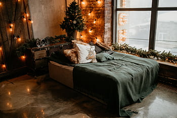 A warm and decorated bedroom featuring a Christmas tree and cozy bedding with soft lighting. HD wallpaper