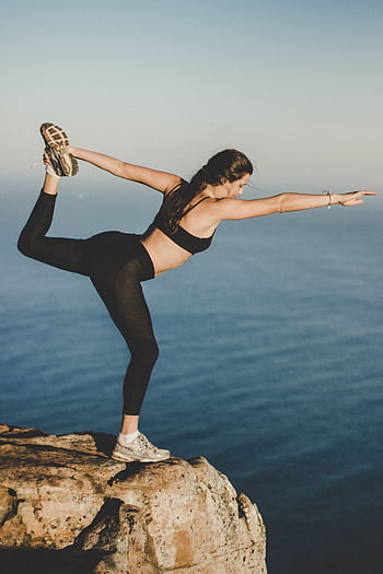 Woman practicing yoga in Dancer's pose on a cliff with ocean view, Cape Town. HD phone wallpaper