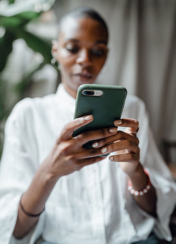 A woman in a white blouse using her smart indoors, showing a thoughtful and calm mood. HD phone wallpaper