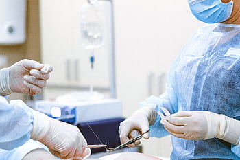Healthcare professionals in protective gear engaged in a surgical procedure. HD wallpaper
