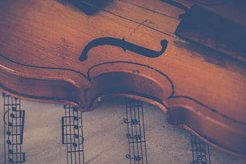 Artistic close-up of a violin on sheet music, highlighting musical elegance. HD wallpaper