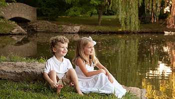 Smiling Cute Boy And Girl Is Sitting On Green Grass Wearing White Dress In Lake Background Cute HD wallpaper