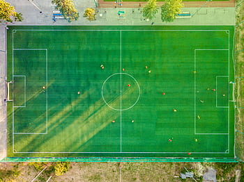 Aerial shot of a soccer game with players on a vibrant green field. HD wallpaper