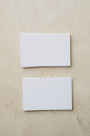 Top view of neat stacks of blank business cards on a light wooden surface, perfect for branding or advertising concepts. HD phone wallpaper