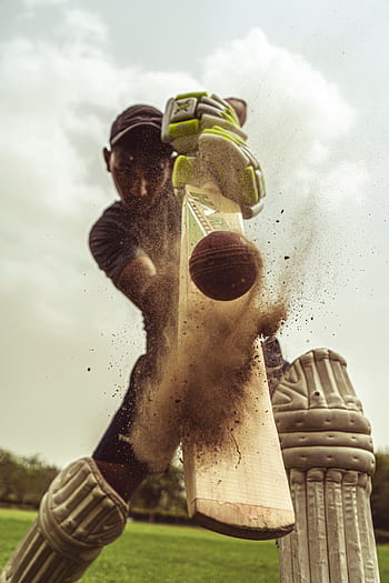 Cricketer in motion striking the ball with intense focus, clouds of dust captured. HD phone wallpaper