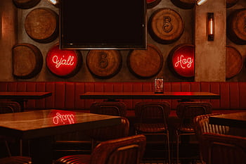 Vintage-style bistro interior with wooden barrels and neon signs, creating a warm and cozy ambiance. HD wallpaper