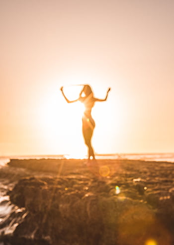 A woman celebrates at sunset on a beach in San Diego, creating a stunning silhouette. HD phone wallpaper