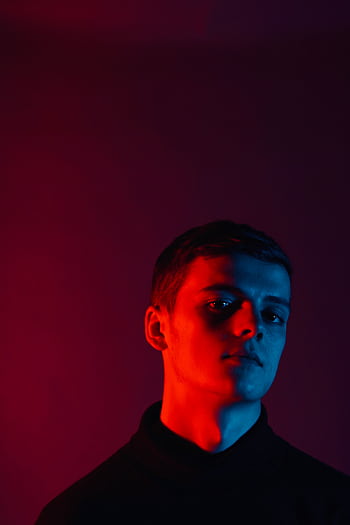 Striking studio portrait of a young man with red and blue lighting, conveying a moody atmosphere. HD phone wallpaper