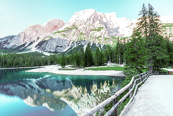 Stunning view of an alpine lake with clear reflections of snow-capped mountains and lush green trees. HD wallpaper