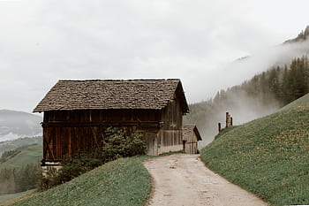 A serene wooden house on a misty mountain slope captures the essence of rural tranquility. HD wallpaper