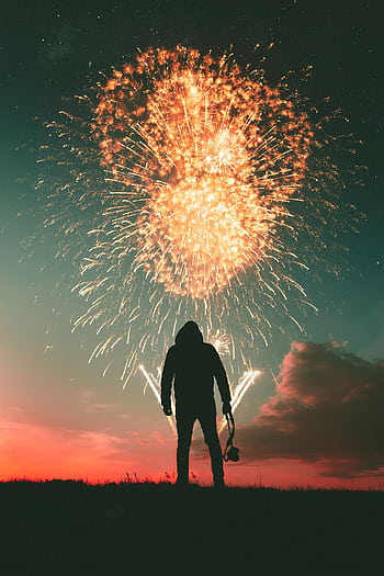Silhouette of a person with a camera watching a fireworks display under a night sky. HD phone wallpaper