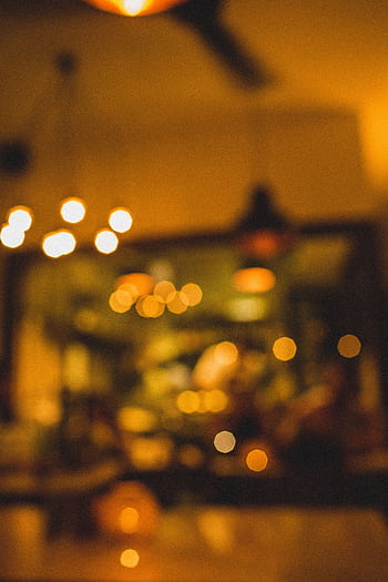 Defocused view of warm ambient lighting in a cozy café interior, perfect for a relaxing evening atmosphere. HD phone wallpaper