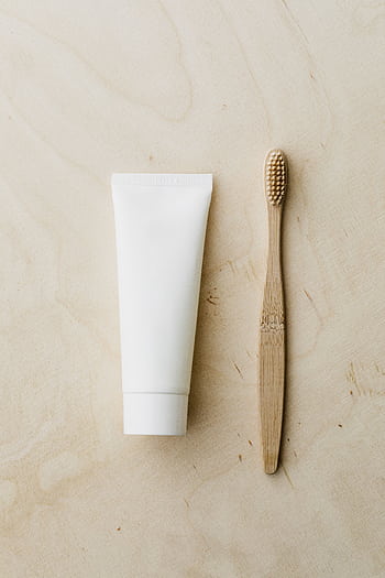 Minimalist flat lay featuring a bamboo toothbrush and blank toothpaste tube for eco-friendly hygiene. HD phone wallpaper