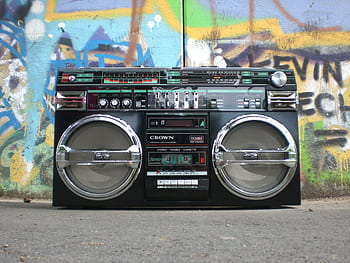 Classic vintage boombox placed in front of a vibrant graffiti-covered wall. Perfect for retro lovers. HD wallpaper
