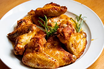 Golden-brown chicken wings garnished with fresh herbs, perfect for a tasty meal. HD wallpaper